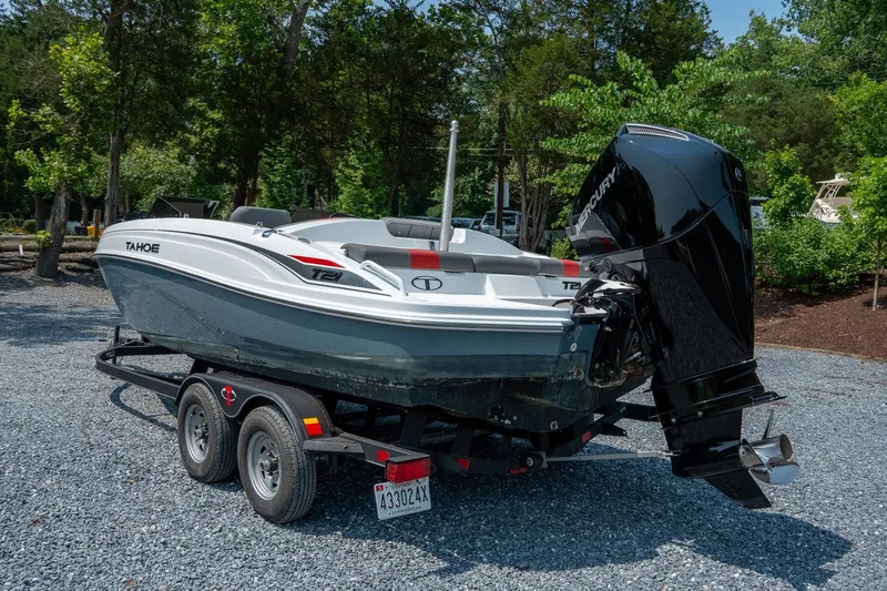 The Image of 2024 Tahoe T21 boat on trailer, parked outdoors with trees in the background. - 0