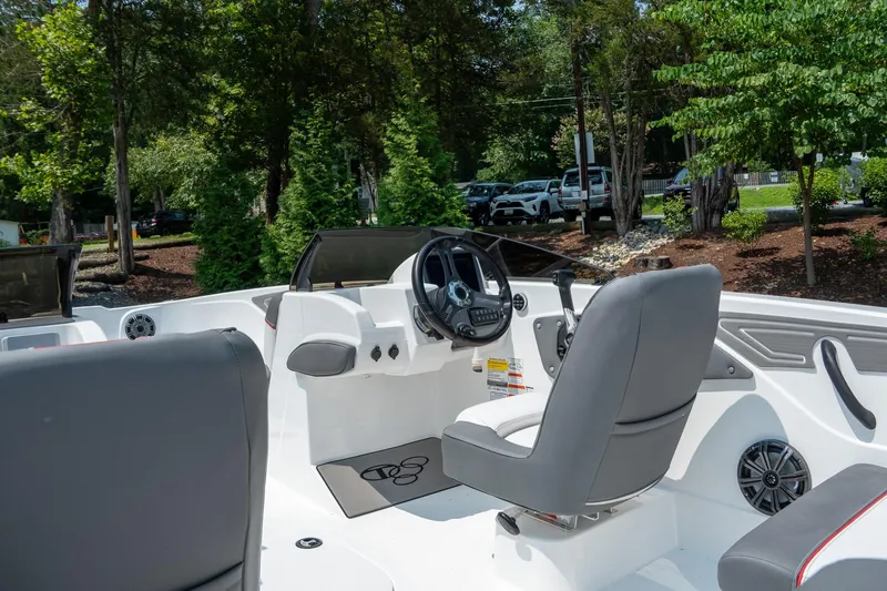 Slide: The Image of 2024 Tahoe T21 boat interior with steering wheel and seating, surrounded by lush greenery. - 10