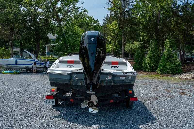 Slide: The Image of 2024 Tahoe T21 boat on trailer in a wooded area, rear view. - 6