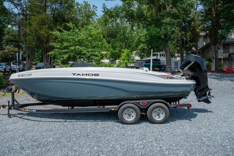 Slide: The Image of 2024 Tahoe T21 boat on trailer, parked outdoors with trees in the background. - 4