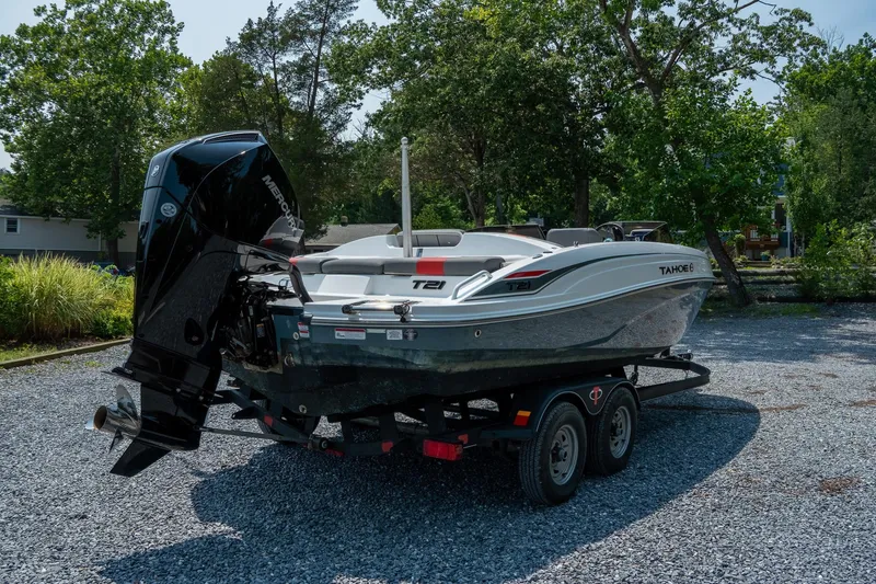 Slide: The Image of 2024 Tahoe T21 boat on trailer, parked outdoors with trees in background. - 8