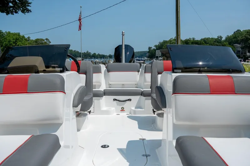 Slide: The Image of 2024 Tahoe T21 boat interior with red and gray seating, docked by a lake. - 11