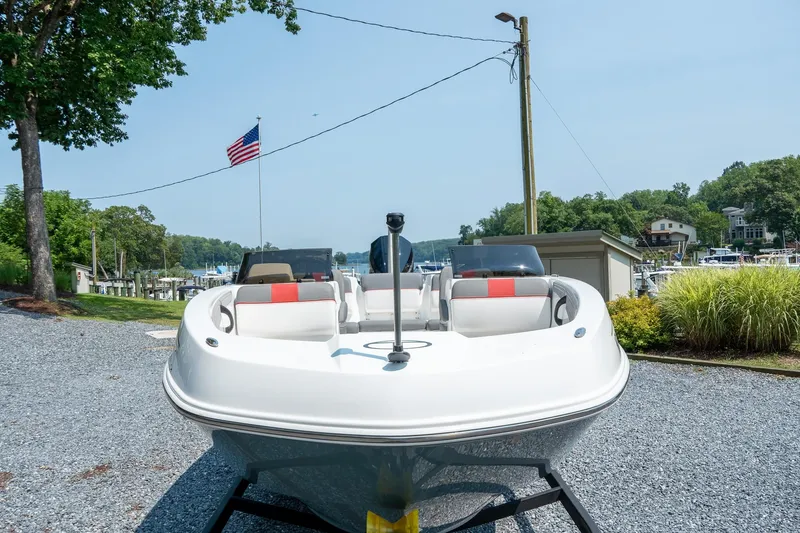 Slide: The Image of 2024 Tahoe T21 boat on trailer, parked near marina with American flag and greenery. - 15