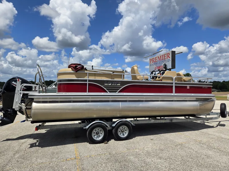 Slide: The Image of A 2020 Lowe SF 232 pontoon boat on a trailer, featuring a red and beige design. - 7
