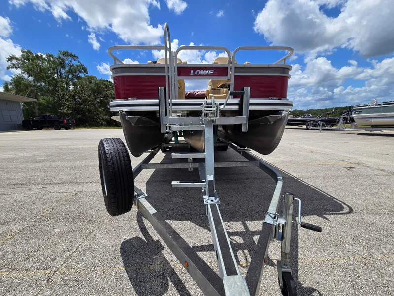 Slide: The Image of A 2020 Lowe SF 232 pontoon boat on a trailer, parked under a blue sky. - 10
