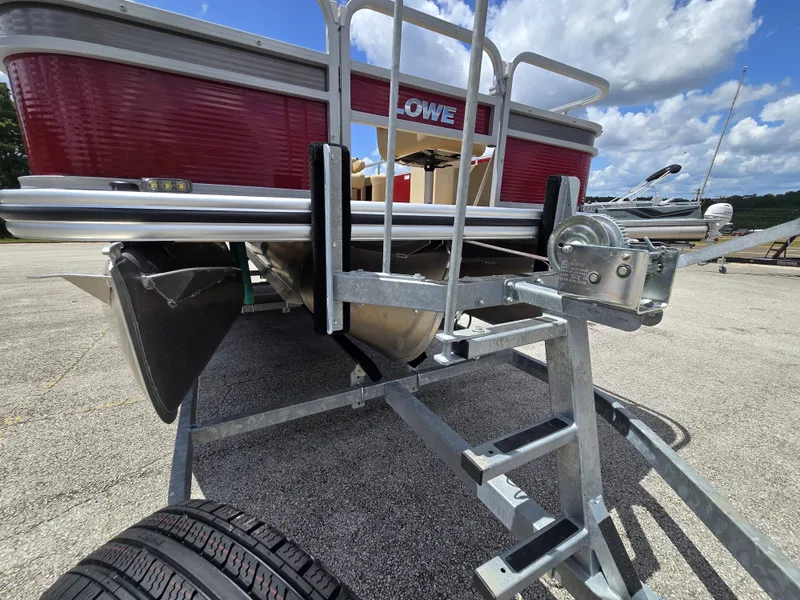 Slide: The Image of A 2020 Lowe SF 232 pontoon boat on a trailer, featuring a red hull and blue sky. - 28