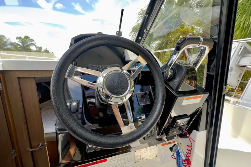 Slide: The Image of Steering wheel and controls of a 2018 Jeanneau NC 895 boat cockpit. - 22