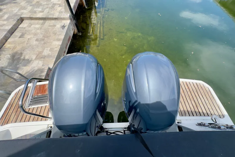 Slide: The Image of Twin outboard motors on a 2018 Jeanneau NC 895 boat docked by the water. - 44