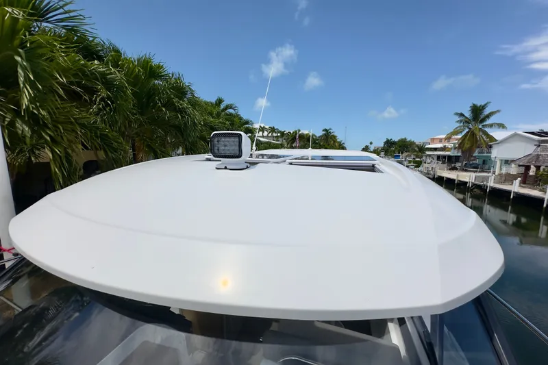 Slide: The Image of 2018 Jeanneau NC 895 boat roof with spotlight, surrounded by palm trees and waterfront homes. - 39