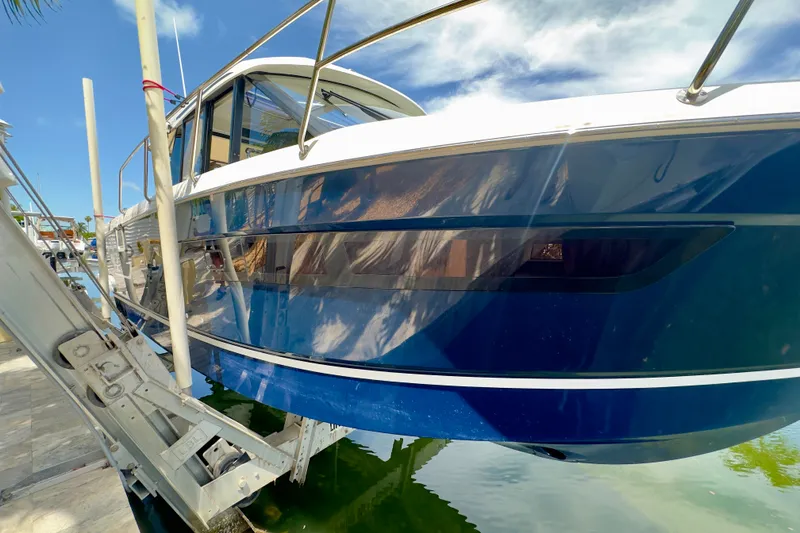 Slide: The Image of 2018 Jeanneau NC 895 boat docked, reflecting blue sky and clouds. - 14