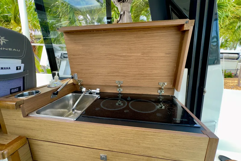 Slide: The Image of 2018 Jeanneau NC 895 boat kitchen with sink and stove, featuring wooden cabinetry. - 45