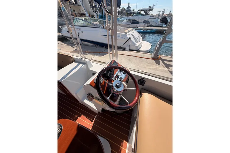 Slide: The Image of Steering wheel of a 2018 Duffy Cuddy Cabin 22 boat docked at a marina. - 24