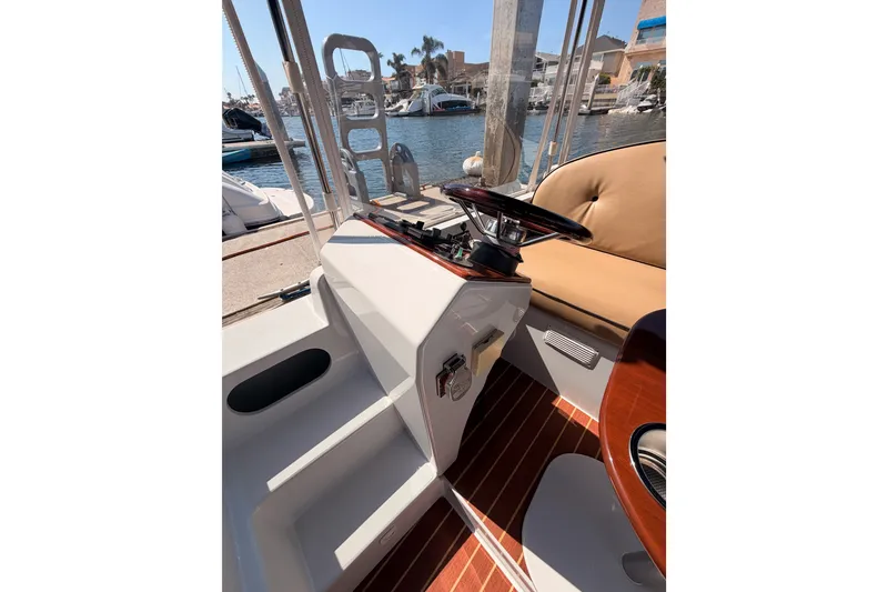 Slide: The Image of 2018 Duffy Cuddy Cabin 22 boat interior with steering wheel and seating, docked at marina. - 22