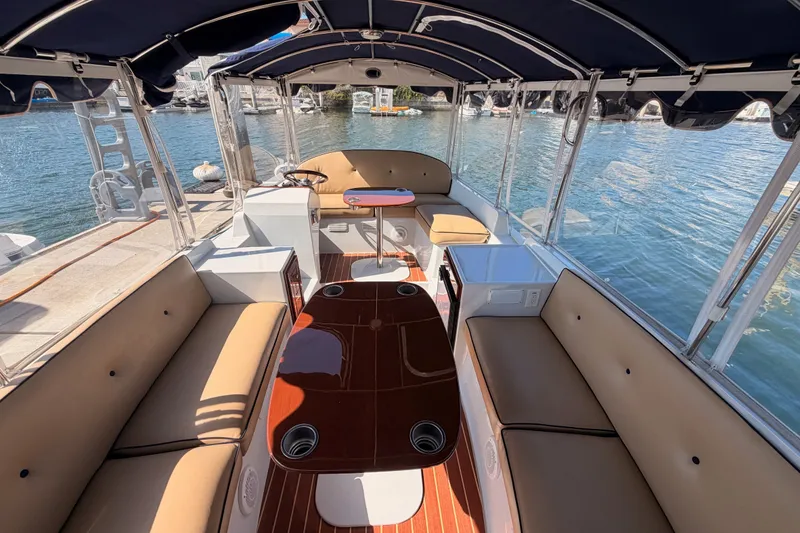 Slide: The Image of 2018 Duffy Cuddy Cabin 22 boat interior with seating, table, and canopy on the water. - 18
