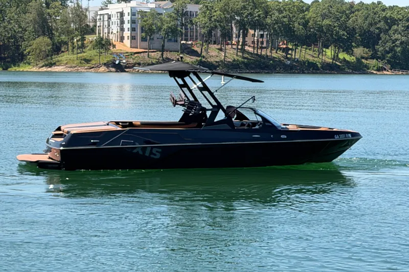 Slide: The Image of 2022 Axis T23 boat cruising on a serene lake with lush greenery in the background. - 9