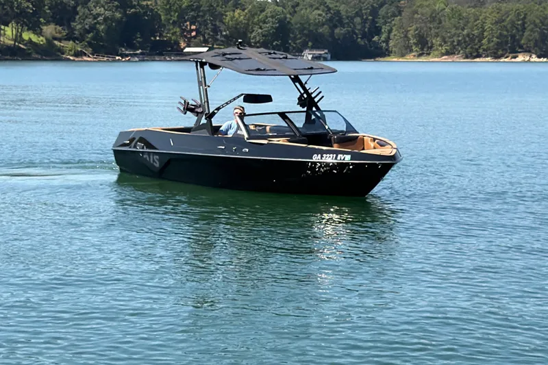Slide: The Image of 2022 Axis T23 boat cruising on a serene lake with lush green shoreline. - 15