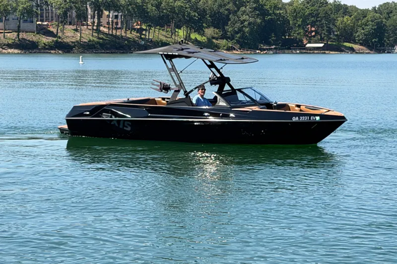 Slide: The Image of 2022 Axis T23 boat cruising on a serene lake with lush green shoreline. - 12