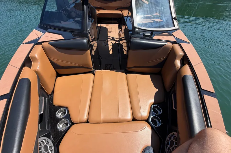 Slide: The Image of 2022 Axis T23 boat interior with tan leather seating and cup holders on a sunny day. - 26