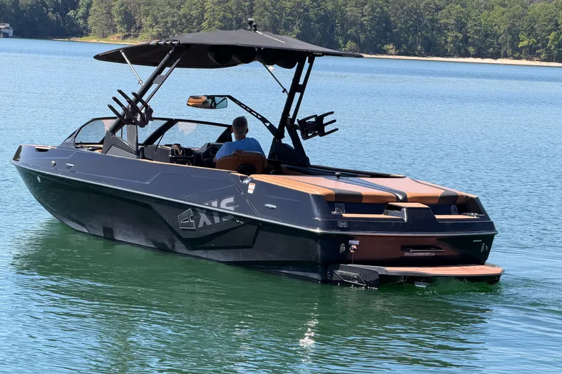 Slide: The Image of 2022 Axis T23 boat cruising on a serene lake with lush forest backdrop. - 3