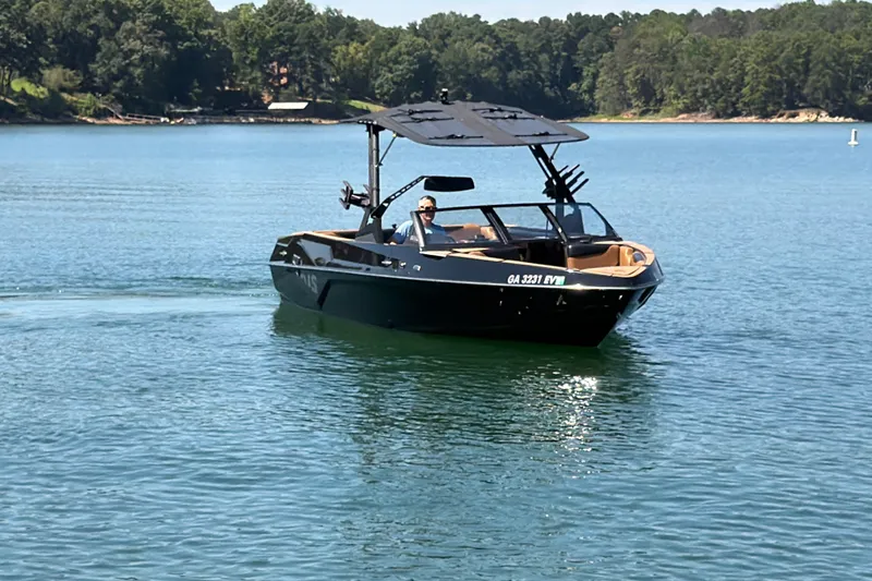 Slide: The Image of 2022 Axis T23 boat cruising on a serene lake with lush green shoreline. - 17