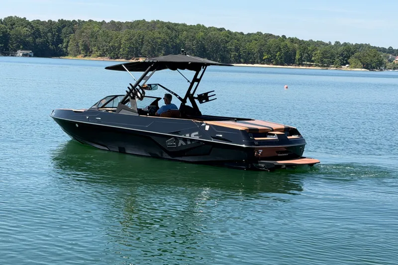 Slide: The Image of 2022 Axis T23 boat cruising on a serene lake with lush forest backdrop. - 2