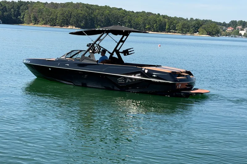 Slide: The Image of 2022 Axis T23 boat cruising on a serene lake with lush green shoreline. - 1