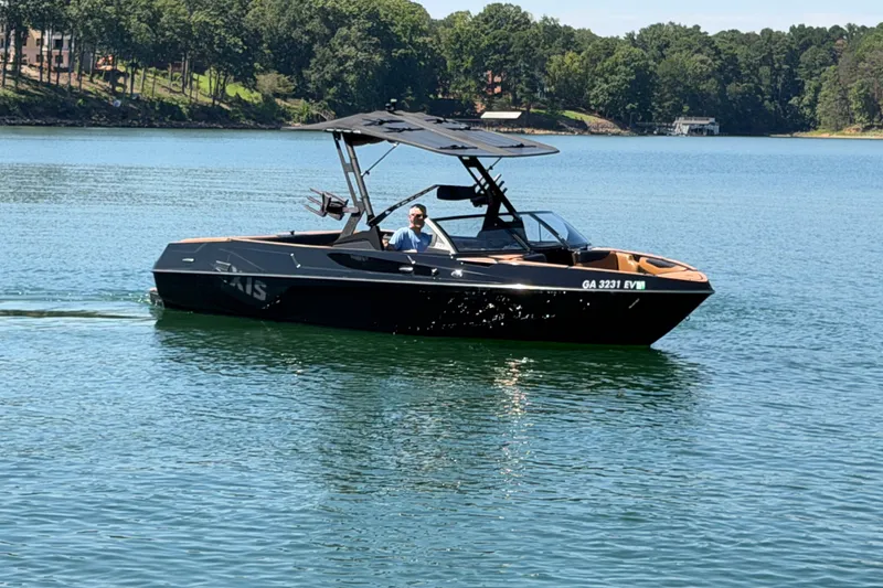 Slide: The Image of 2022 Axis T23 boat cruising on a serene lake with lush green shoreline. - 14