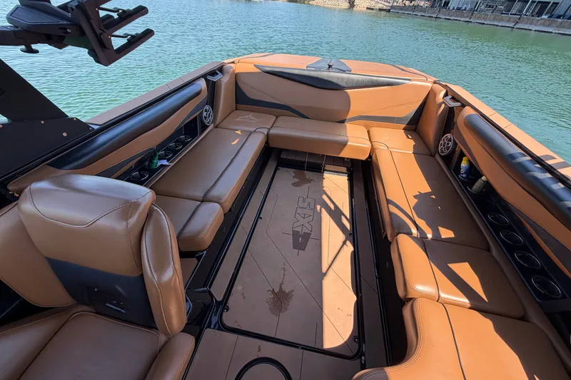Slide: The Image of 2022 Axis T23 boat interior with tan leather seating, docked on a calm lake. - 20