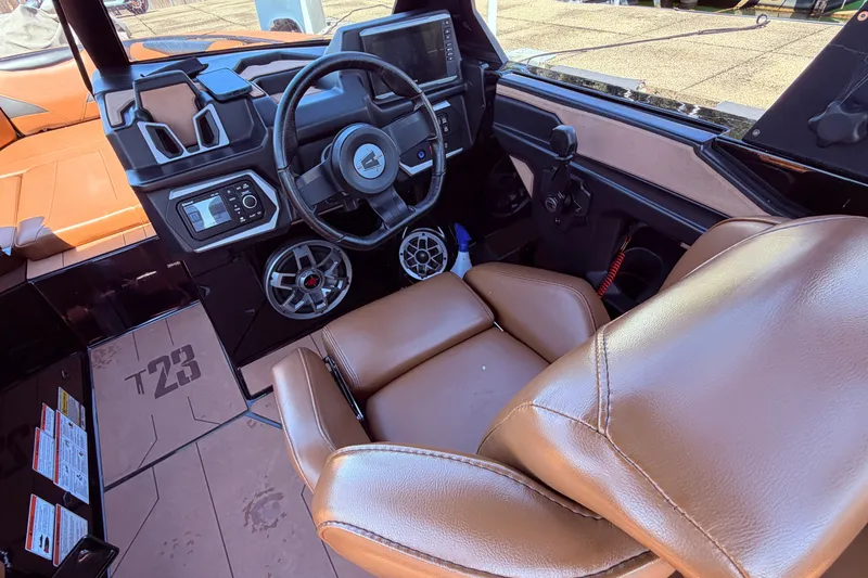 Slide: The Image of Interior of 2022 Axis T23 boat featuring steering wheel, dashboard, and brown seating. - 18