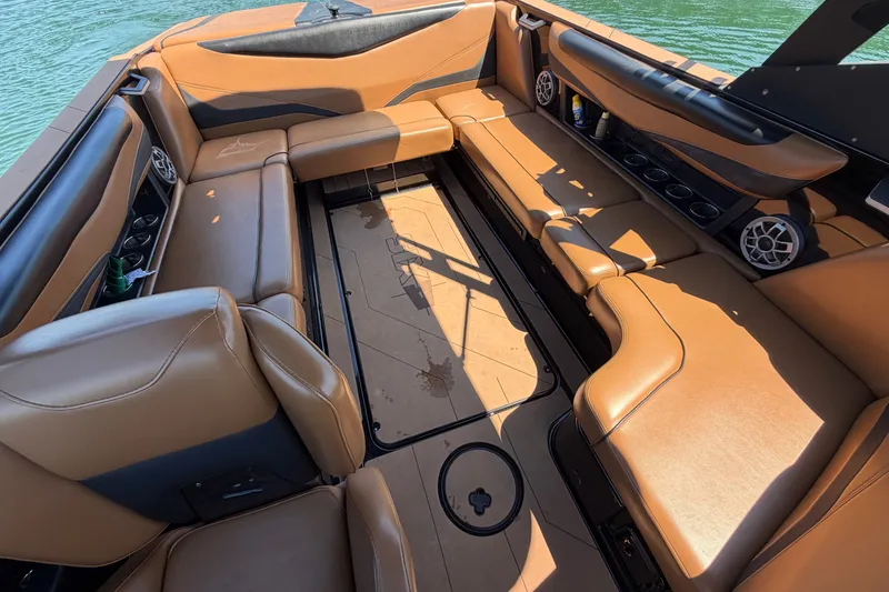 Slide: The Image of 2022 Axis T23 boat interior with tan leather seating and cup holders on a sunny day. - 23