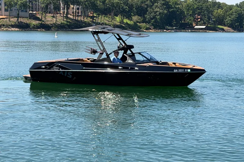 Slide: The Image of 2022 Axis T23 boat cruising on a serene lake with lush green shoreline. - 11