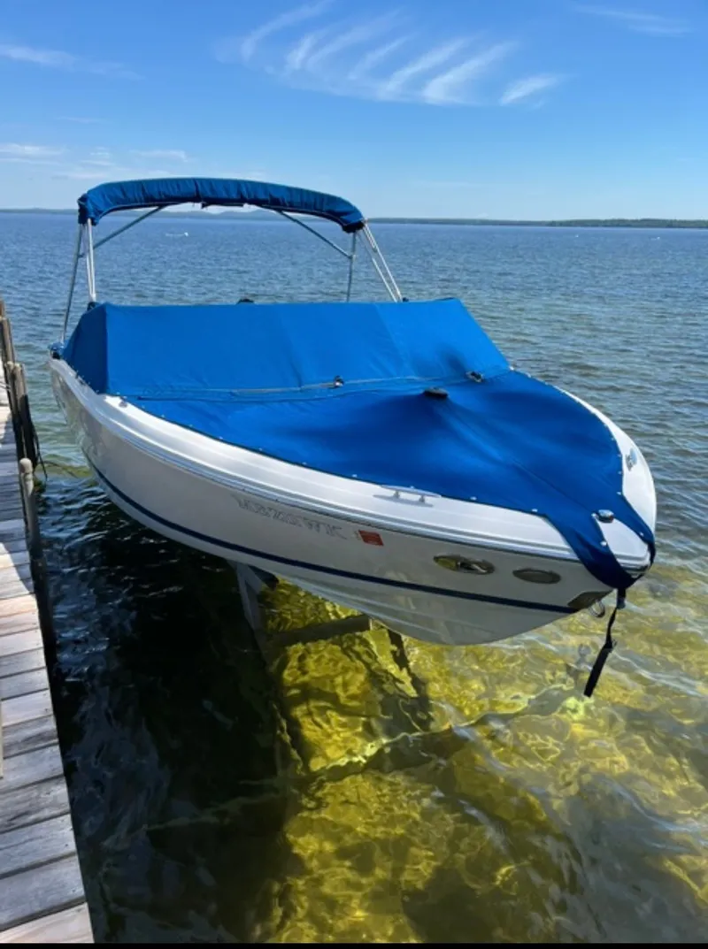 Slide: The Image of A white boat with a blue cover is docked in clear water. - 15