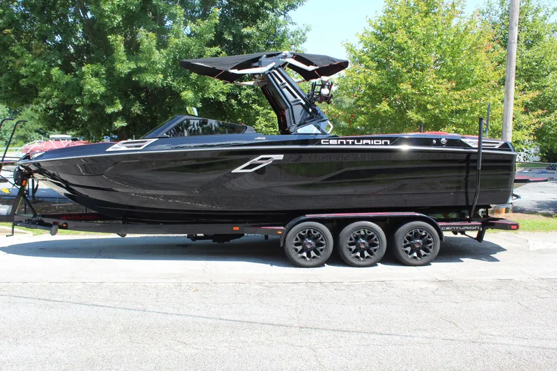 The Image of A black Centurion Ri 265 boat from 2022 on a trailer, surrounded by trees. - 1