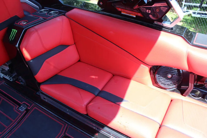 Slide: The Image of Red leather seating in a 2022 Centurion Ri 265 boat, featuring black accents and cup holders. - 15