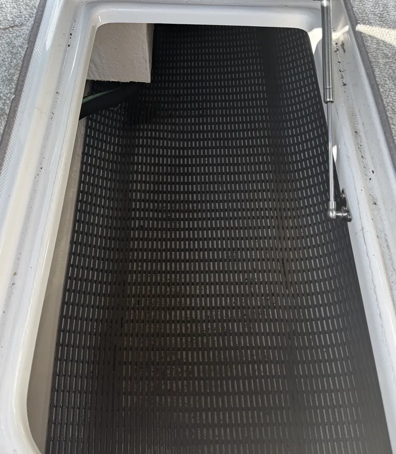 Slide: The Image of An open storage compartment with a black grid floor and hydraulic arm. - 28