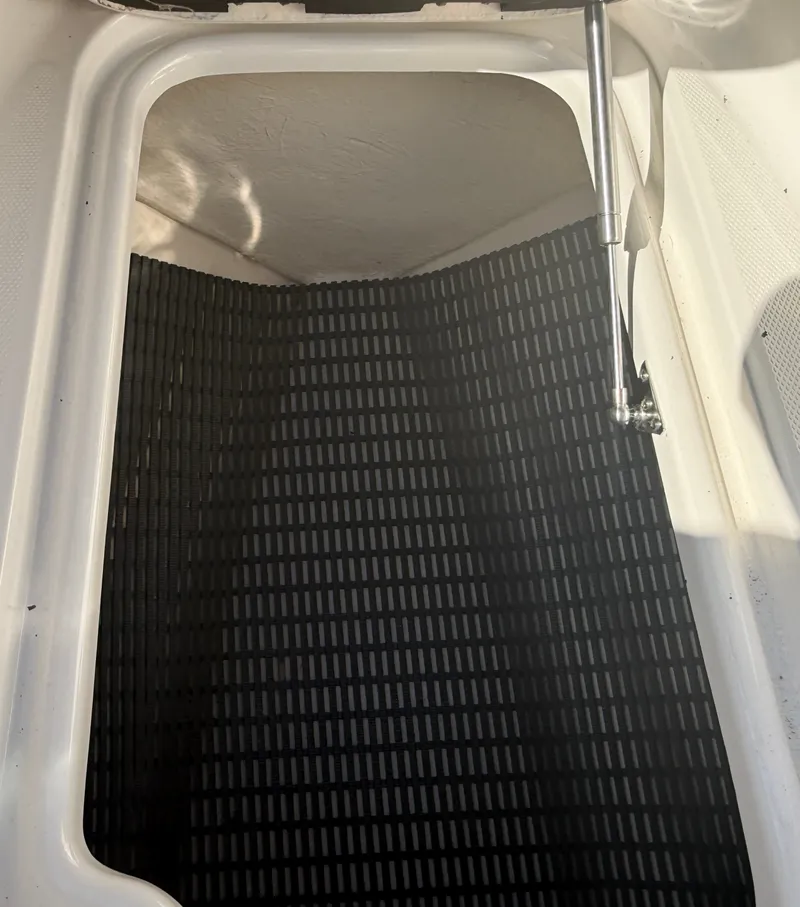 Slide: The Image of An open storage compartment with a black rubber mat and hydraulic arm. - 27
