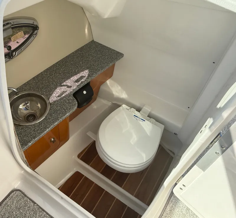 Slide: The Image of The image shows the bathroom of a 2013 Chaparral 264 Sunesta with a sink and toilet. - 22
