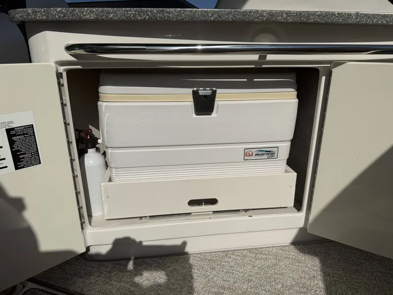Slide: The Image of A built-in storage compartment on a 2013 Chaparral 264 Sunesta boat with a cooler and fire extinguisher. - 30