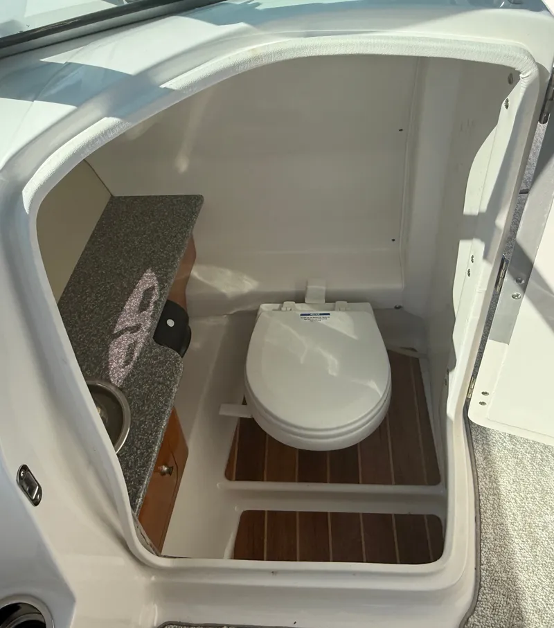 Slide: The Image of The image shows a compact boat toilet with a wooden floor and a small countertop. - 21