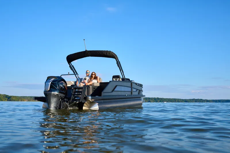 The Image of A modern pontoon boat with a black hull and sunshade cruising on a calm lake. - 1