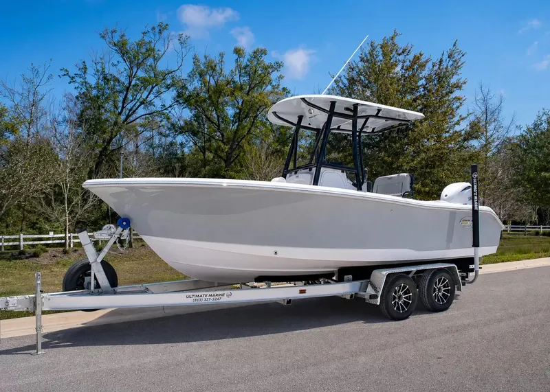 The Image of A 2027 Sea Hunt Ultra 219 boat on a trailer, surrounded by trees and a blue sky. - 1