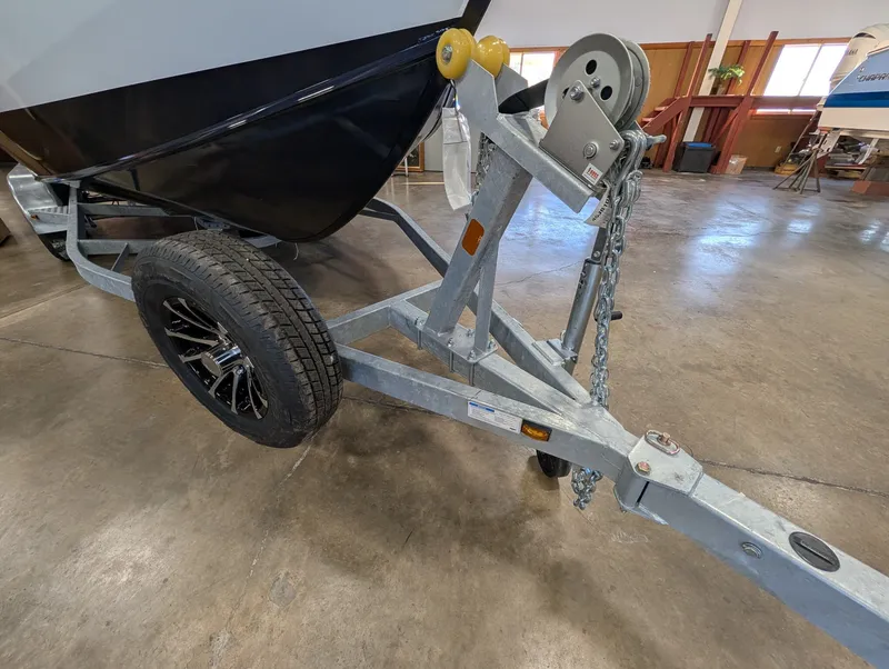 Slide: The Image of A boat trailer with a black boat on it, parked indoors. - 21