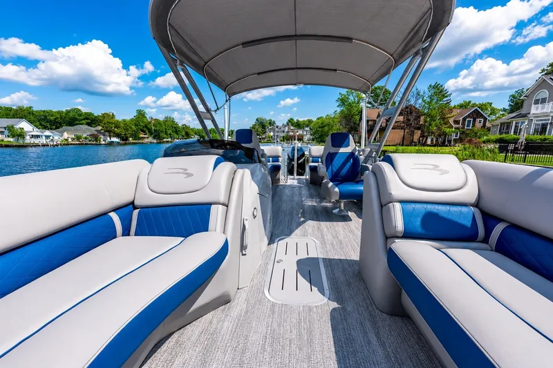 Slide: The Image of 2022 Bennington L 24 Quad Bench pontoon boat with luxurious seating on a scenic lake. - 7