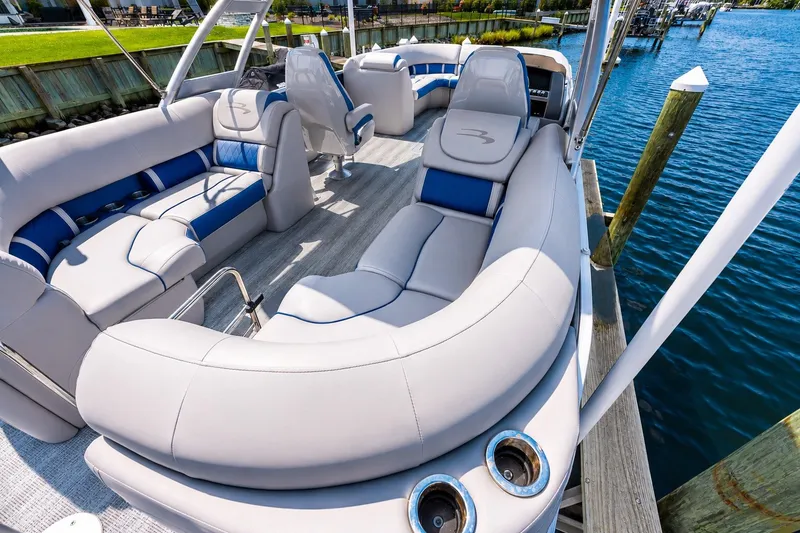 Slide: The Image of Luxurious 2022 Bennington L 24 Quad Bench pontoon boat with plush seating docked by the water. - 5
