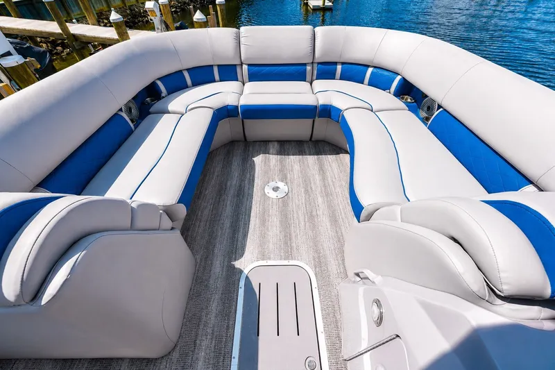 Slide: The Image of 2022 Bennington L 24 Quad Bench interior with plush seating and blue accents on a sunny day. - 3