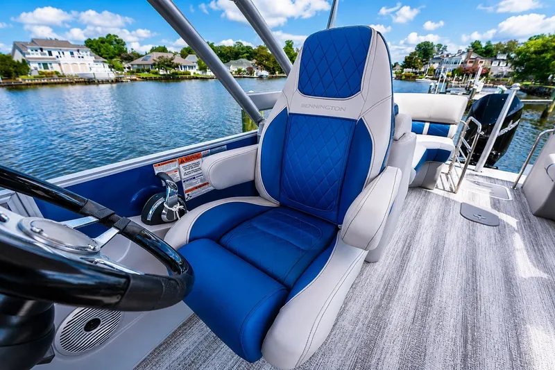 Slide: The Image of 2022 Bennington L 24 Quad Bench boat interior with blue and white captain's chair. - 11