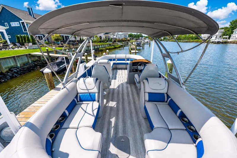 Slide: The Image of 2022 Bennington L 24 Quad Bench pontoon boat docked by a scenic waterfront. - 4