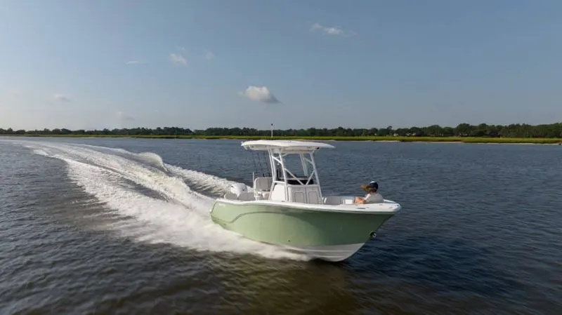The Image of A Sea Fox 228 Commander boat speeds across calm water, surrounded by green landscape. - 1