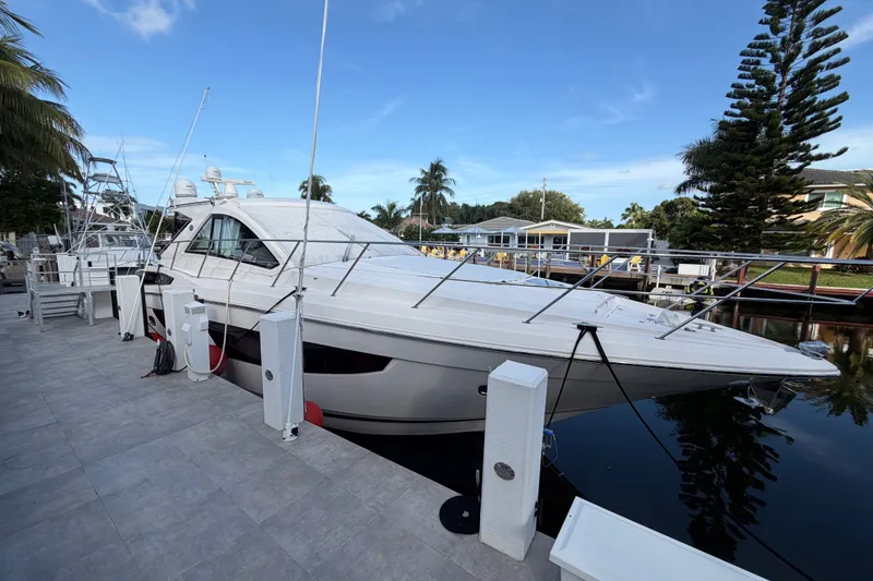 Slide: The Image of 2018 Regal 53 Sport Coupe yacht docked by a waterfront, surrounded by palm trees. - 8
