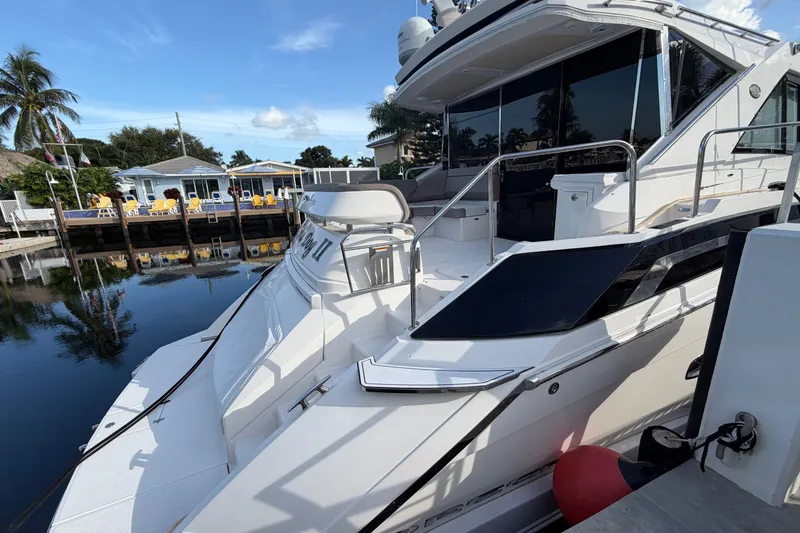 Slide: The Image of 2018 Regal 53 Sport Coupe yacht docked by waterfront homes, reflecting on calm water. - 14